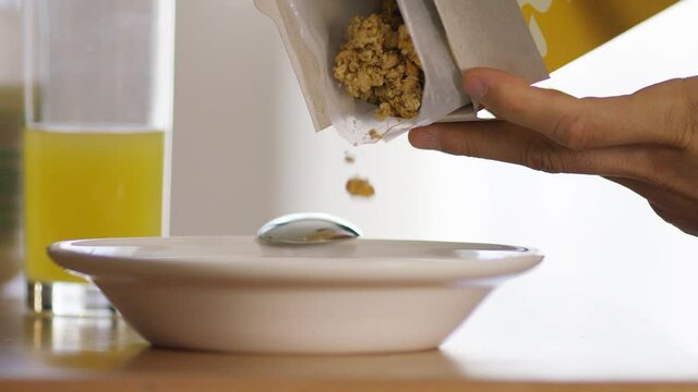 Crunchy cereal clusters being poured into a breakfast bowl, in slow motion