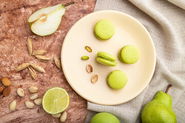 Green macarons or macaroons cakes with cup of coffee on a brown concrete background. Top view.