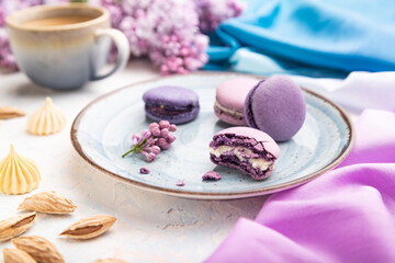 Purple macarons or macaroons cakes with cup of coffee on a white concrete background. Side view, selective focus.