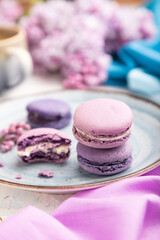 Purple macarons or macaroons cakes with cup of coffee on a white concrete background. Side view, selective focus.