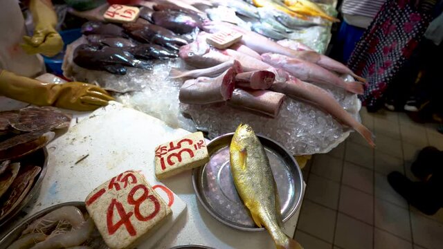 Hand of a fishmonger weighing a fish on the fish market of Hong Kong