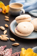 Meringues cakes with cup of coffee on a black concrete background. Side view, selective focus.
