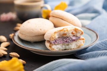 Meringues cakes with cup of coffee on a black concrete background. Side view, selective focus.