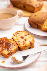 Homemade cake with raisins, almonds, soft caramel and a cup of coffee on a white wooden background. Side view, selective focus.