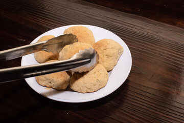tongs holding a bread roll from a group of bread