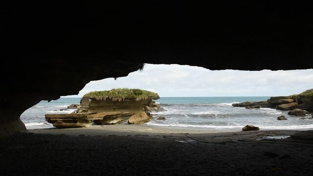 The sea and beach at the end of the Truman Track, Paparoa National Park, New Zealand, viewed from within a massive cavern in the cliff.