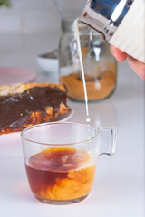 Cup of Tea falling splash of milk, on white background with chocolate puff pastry, whole grain panela. white brick wall background