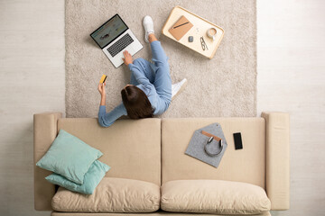 Young brunette female resting on the floor by couch during online shopping