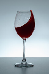 Splash of wine in a glass on a gray background.