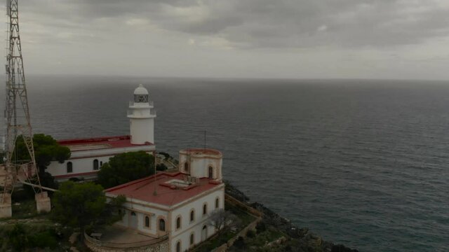 Aerial white lighthouse cloudy day water cliff tower Spain