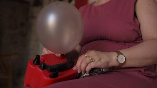 Caucasian woman using electronic air balloon pump inflating inside