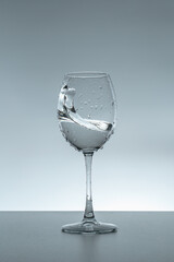 Splash of water in a glass on a gray background.