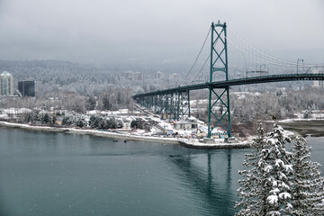 Suspension bridge over the ocean bay in winter. Lions gate bridge in a foggy snowy day between Stanley park and North Vancouver. British Columbia. Canada 