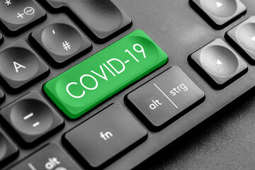 grüne Covid 19 Taste auf einer dunklen Tastatur