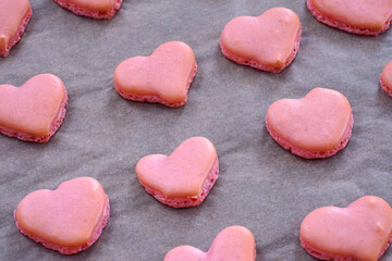 Obraz premium Pink heart homemade macaron cookies on parchment paper on a baking sheet
