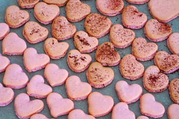 Obraz na płótnie Canvas Pink heart homemade macaron cookies on parchment paper on a baking sheet
