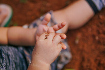 the boy's hand was playing on the dirty ground