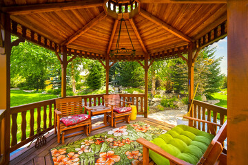 View of a wooden gazebo in the landscaped garden of an upscale home. - obrazy, fototapety, plakaty