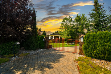 An upscale luxury estate with a closed security gate at sunset.
