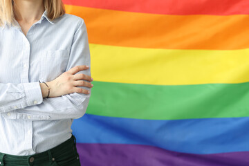 Woman stands with folded arms against background of lgbt flag