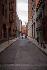Two people walking down a small city street with stone roads