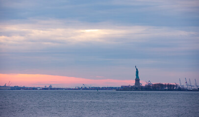 Naklejka premium Pink ocean sunset with statue of liberty in background