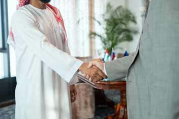 Successful Arabian businessman in national attire greeting his foreign partner