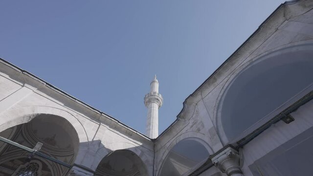 Bottom view of a white temple details with arches and long spire. Action. Beautiful historic building on blue sky background.
