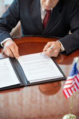 Mature American delegate in formalwear bending over contract of partnership