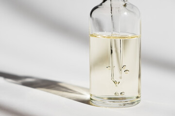 Dropper glass Bottle Mock-Up. Cosmetic pipette on white background. Oil bubbles.