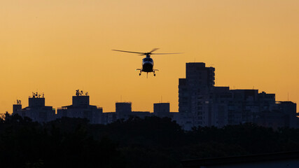 Um helicóptero com prédios da cidade de São Paulo sob o pôr do Sol.