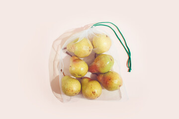 Reusable packaging of products by weight. Pears in a reusable bag close up on a pink background