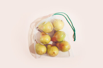 Naklejka na ściany i meble Reusable packaging of products by weight. Pears in a reusable bag close up on a pink background