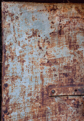 Door made rusty shabby sheet metal, brown rust, scratched peeled off blue paint, textured rough metal surface, rusty metal structure.