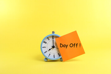Message on Day Off on the piece of paper, and stick to the alarm clock face on the yellow background