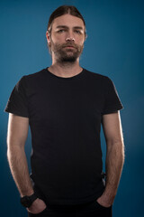 Serious looking male with hands sticking in his pockets is looking at the camera