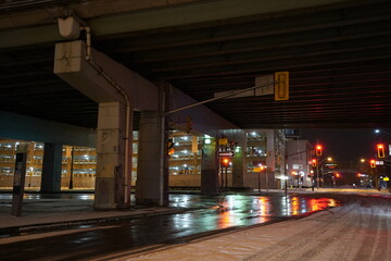 Urban city bridge underpass at night time during rainy day with reflection on the streets and big...