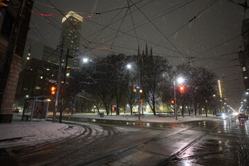 Urban cityscape during night time with city streets during snowstorm in the winter