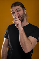 Portrait of a rude male making grimaces while sticking his left arm finger in his nose . Shot...