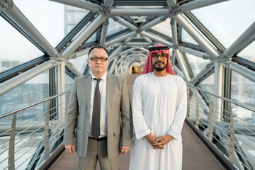 Two confident businessmen or delegates standing next to one another on aisle