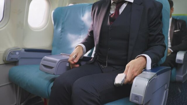 Close-up shot of Caucasian businessman fastening seat belt on airplane