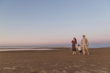 Beach Sunrise with family and dog walking down the beach. Family look linen clothes. Copy space.