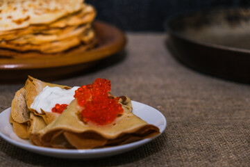 thin pancakes with red caviar on gray canvas napkin. The concept of the Russian carnival Maslenitsa.