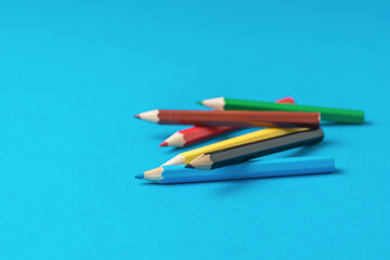Colored pencils scattered on a blue background.