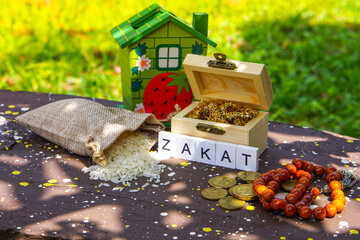 ZAKAT word coin stacked, rice grain in bowl and mini house on nature background. Muslim concept for zakat property, income and "fitrah" zakat. image with selective focus.