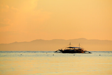 Obraz premium boat at sea during a warm bright sunset