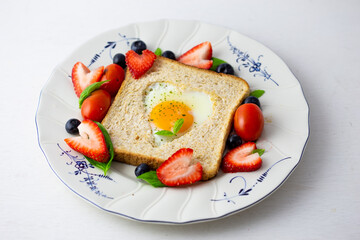 Heart shape sunny side up bread toast breakfast with fruits