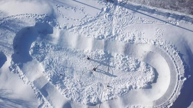 one guy comes to help his friend with spraying water from a hose on to frozen ice track in a snowy skate park