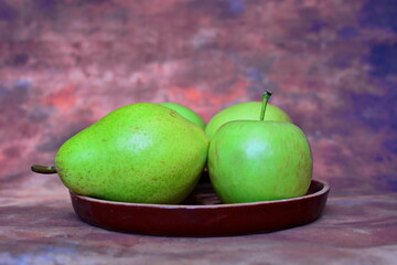 Green fruits, apples and pears on a brown background