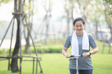 Portrait Asian women middle aged playing scooter in city park in concept healthy strong insurance retire Financial freedom